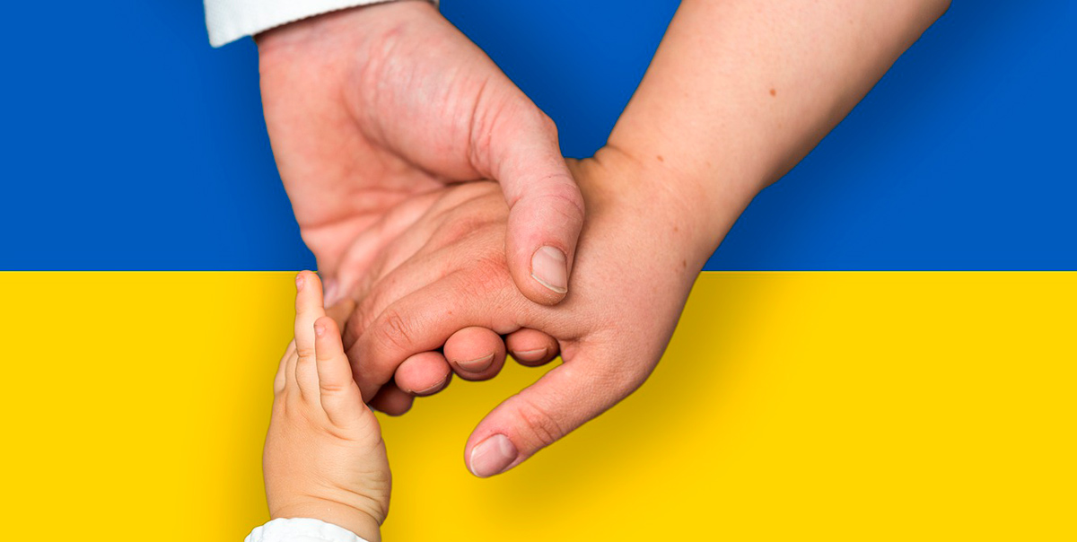 Taustalla Ukrainan lippu, etualalla kahden aikuisen ja yhden lapsen kädet yhdessä